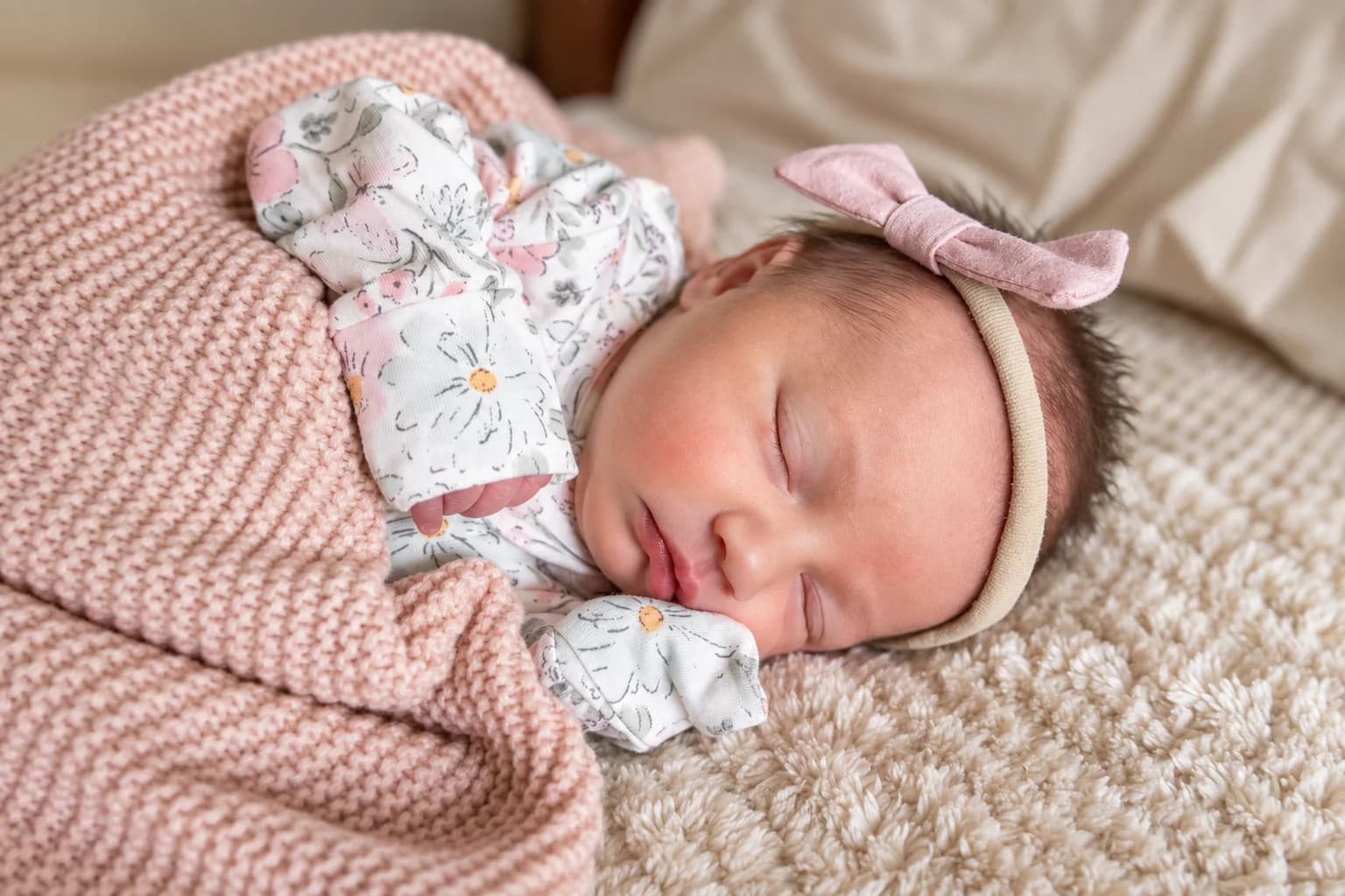 Eliana asleep in a floral sleeper with a pink bow