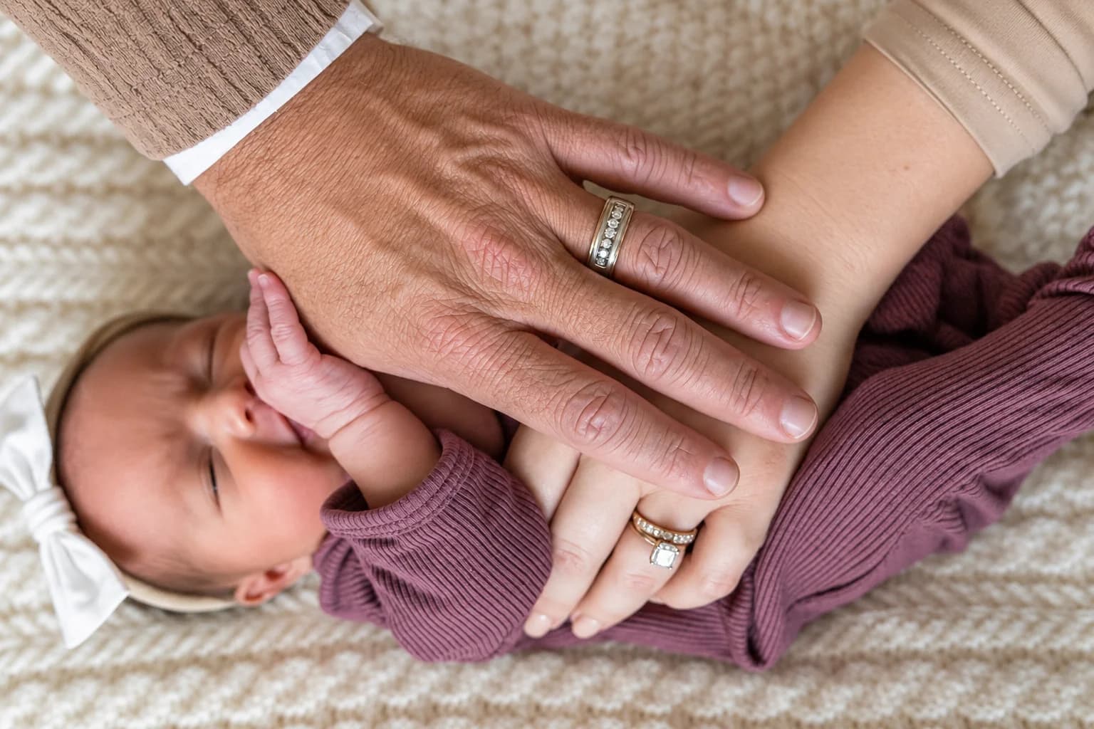 Eliana’s tiny hand held gently between her parents’ hands